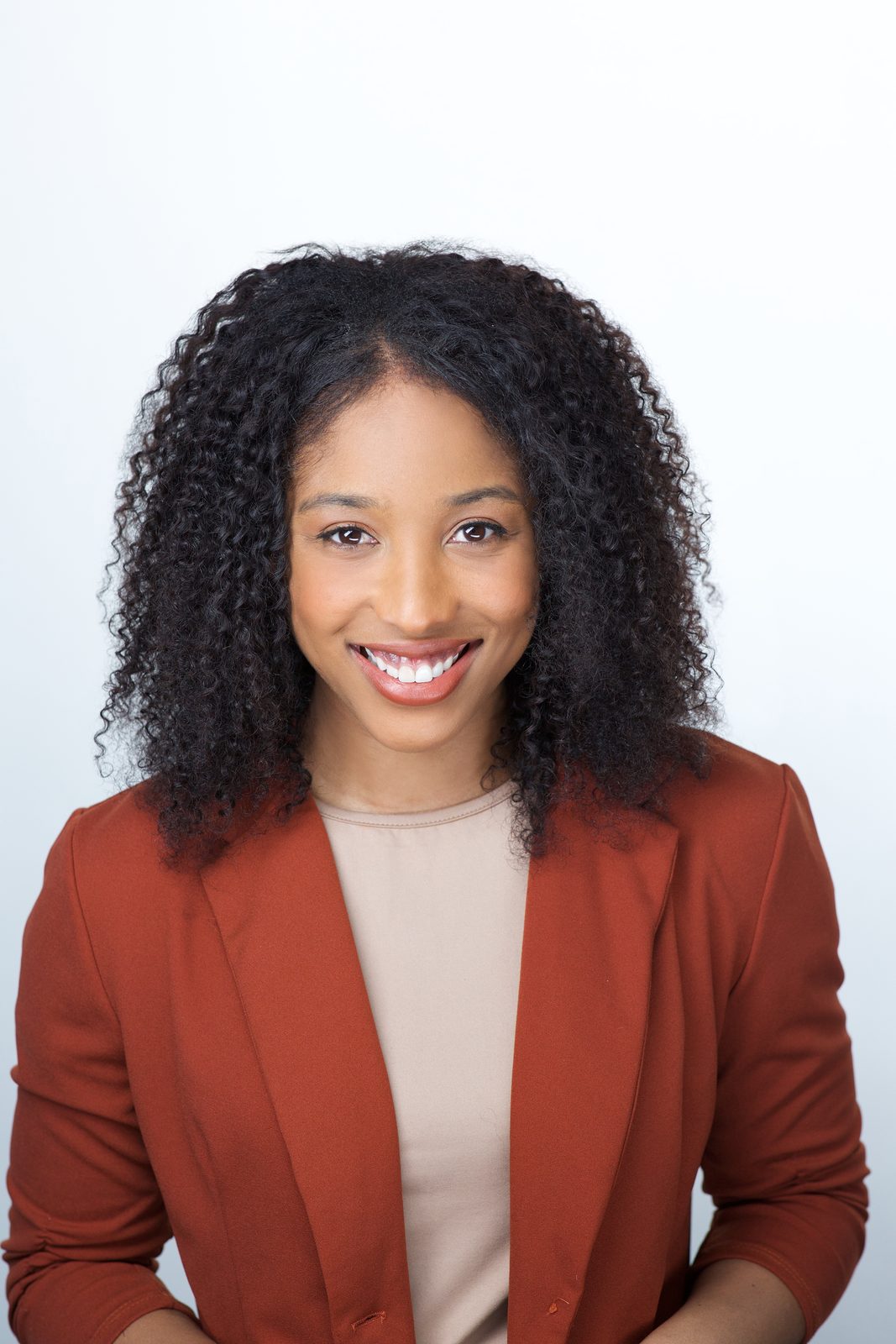 ERAS application photo example — applicant in a terracotta blazer over a beige top, open warm smile, Miami studio