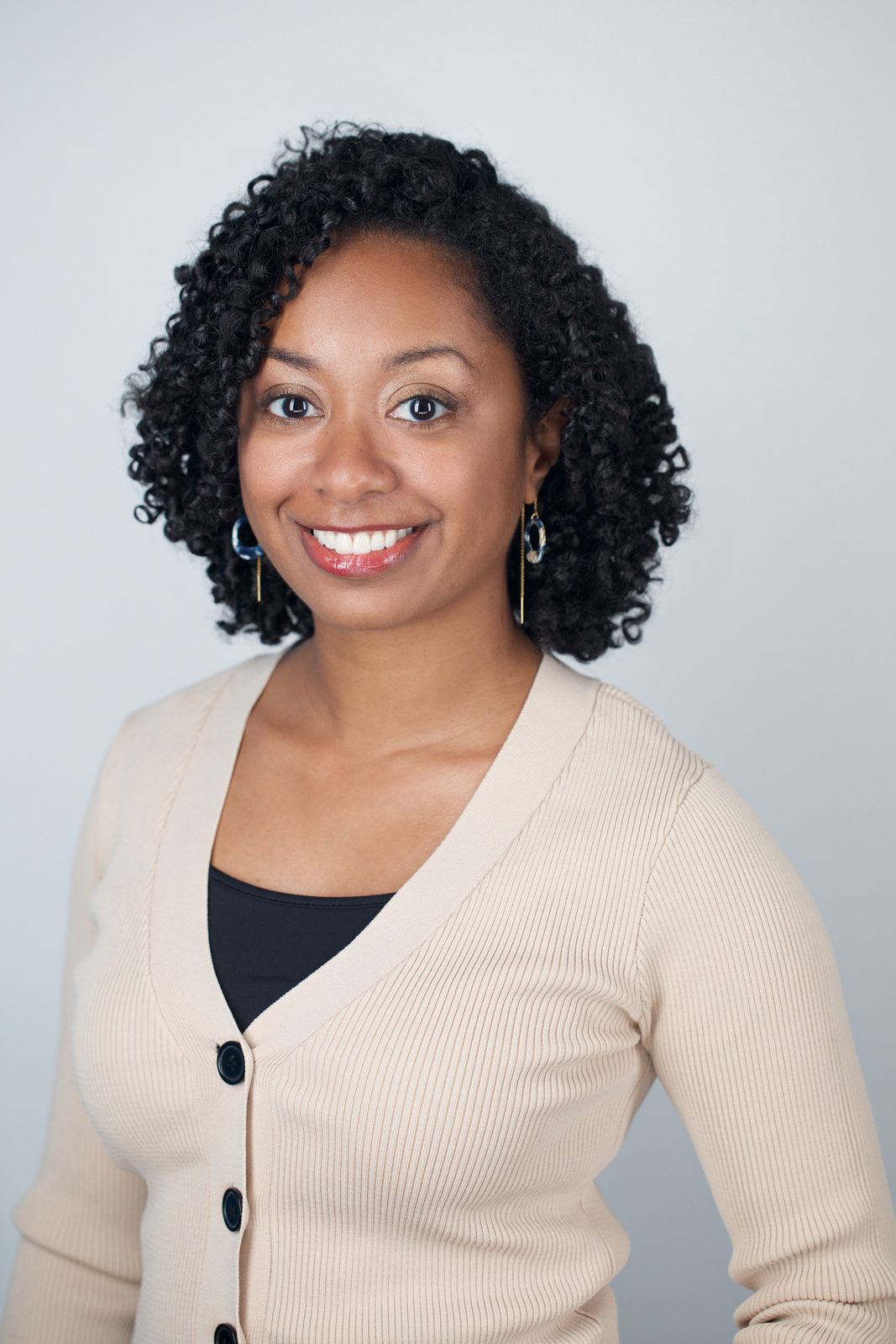 ERAS Plus session headshot — woman in a cream cardigan with curly hair, New York studio