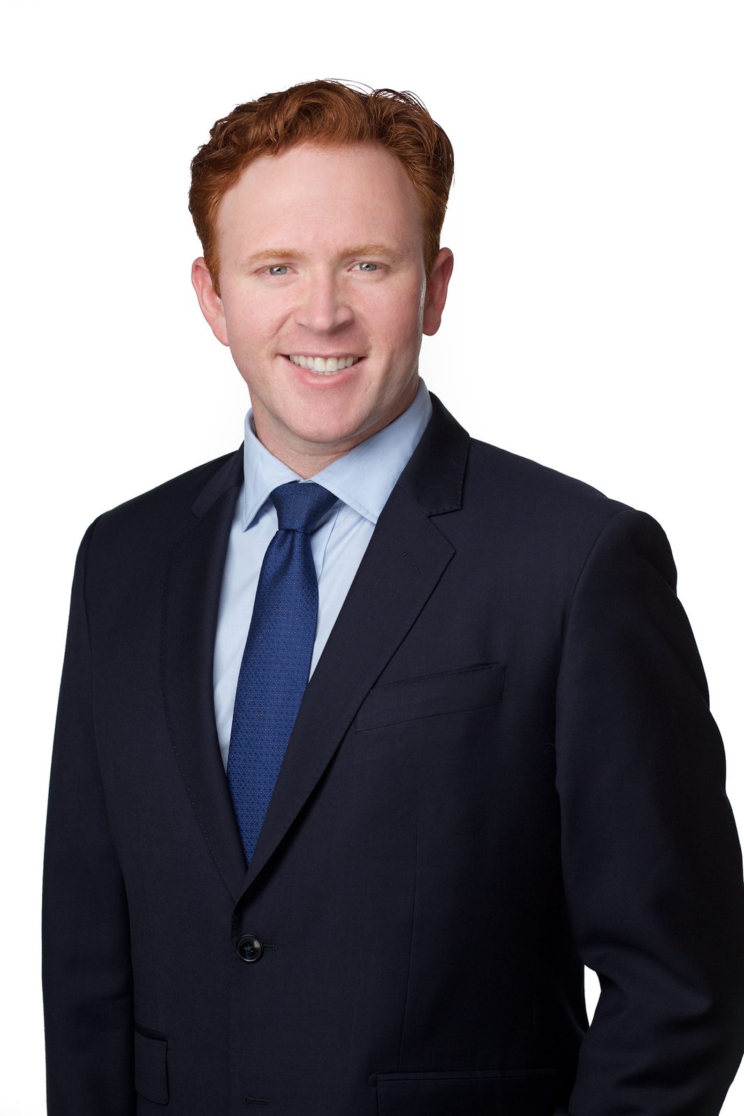 Residency application headshot — man in a navy suit and blue tie, New York studio